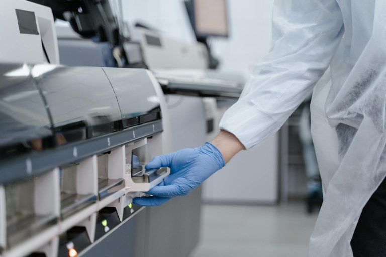 Lab technician in a white coat using equipment with precision in a sterile environment.